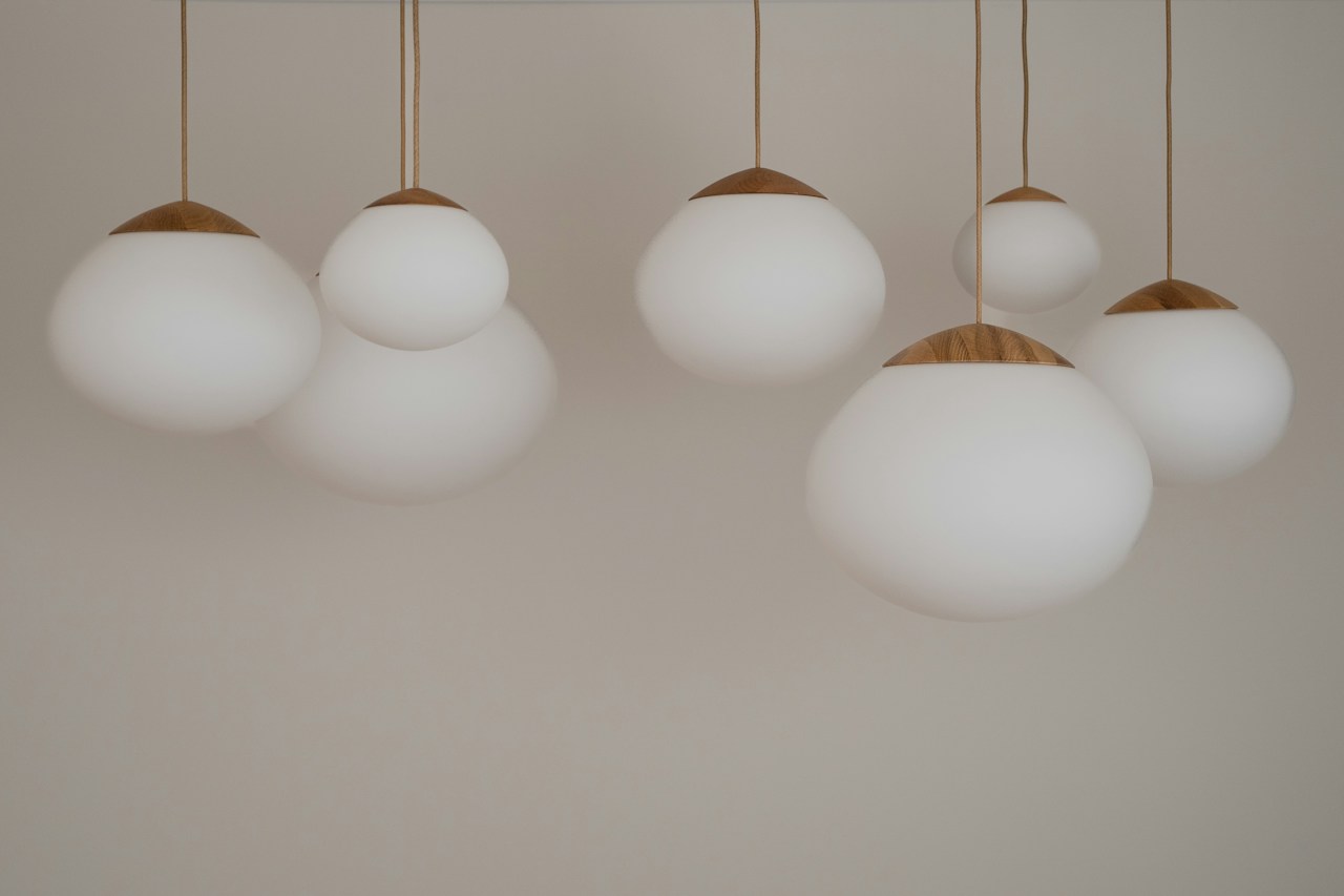 Contemporary pendant lighting with white glass shades and timber accents in an electrical website concept.
